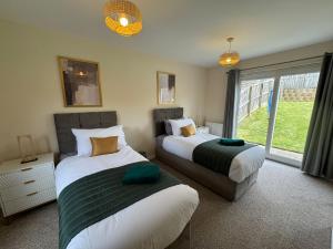 a bedroom with two beds and a window at DONALD'S Townhouse - INVOICE and REDUCED PRICE only via ORION SHORT STAYS DUNDEE, 4 Room, 3 bath, Ring Road Access, Fully Equipped, Free Parking - Freshly Renovated in Dundee