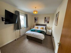 a bedroom with a bed and a flat screen tv at DONALD'S Townhouse - INVOICE and REDUCED PRICE only via ORION SHORT STAYS DUNDEE, 4 Room, 3 bath, Ring Road Access, Fully Equipped, Free Parking - Freshly Renovated in Dundee
