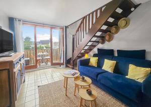uma sala de estar com um sofá azul e uma escada em F2 cosy avec balcon em Merville-Franceville-Plage