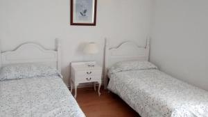 a bedroom with two beds and a table with a night stand at Pension Santa Rita in Santiago de Compostela