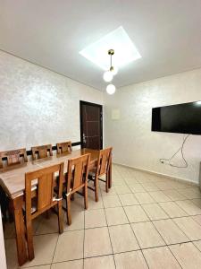 ein Esszimmer mit einem Tisch und Stühlen sowie einem Flachbild-TV in der Unterkunft Appartement avec piscine Bouznika in Bouznika