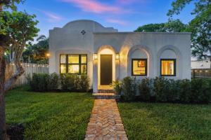 una casa blanca con una puerta amarilla en un patio en 3 Mi to Norton Museum of Art Spanish Revival Gem, en West Palm Beach