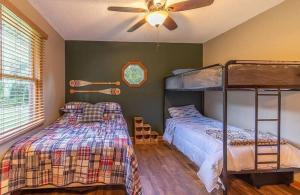 a bedroom with two bunk beds and a ceiling fan at Cherokee Lake Cottage by Staycating in Jefferson City