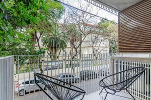 two chairs on a balcony with a view of a street at Deluxe Recoleta Apartments - By Magno in Buenos Aires
