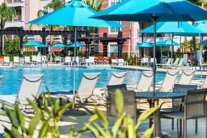 eine Gruppe von Stühlen und Sonnenschirmen neben einem Pool in der Unterkunft Orlando Resort Rentals at Universal Boulevard in Orlando + 37 Fotos