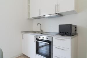 a white kitchen with a microwave and a stove at Stadium Residence in Brescia