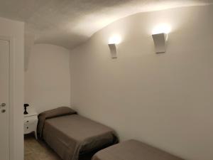 Un dormitorio con dos camas y dos luces en la pared. en Appartamento Luca, en Tiarno di Sotto