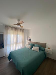 a bedroom with a green bed with a ceiling fan at Apartamentos Finestrat I-II in Cala de Finestrat +11 photos