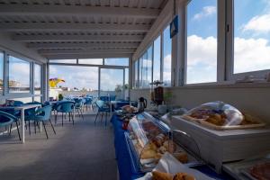 a restaurant with a counter with bread and tables and windows at Pharos in San Vito lo Capo