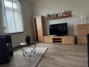 a living room with a flat screen tv on a wooden stand at Ferienwohnungen Heideblick in Gräfenhainichen