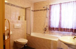 a bathroom with a tub and a toilet and a sink at Landhaus am Golfplatz in Seefeld in Tirol