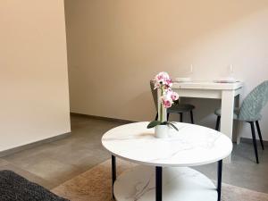 a white table with a vase of flowers on it at ViDa Apartment in Sinzheim