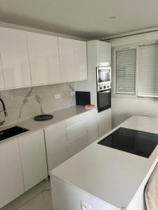 eine weiße Küche mit weißen Schränken und Geräten in der Unterkunft Emmanuel INN 3 in Drancy + 64 Fotos