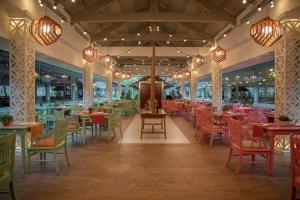 蓬塔卡纳Iberostar Waves Punta Cana - All Inclusive的一间空餐厅,配有桌椅和灯
