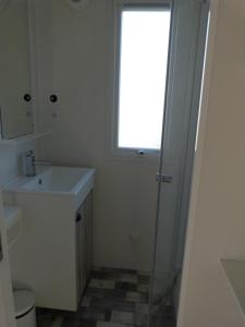 Un baño con lavabo, inodoro y ventana. en Mobilhome 4 chambres 8 places, en Erquy