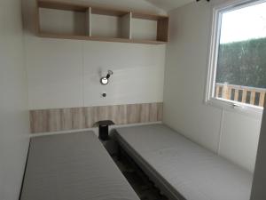 Una pequeña habitación con una cama y una ventana. en Mobilhome 4 chambres 8 places, en Erquy