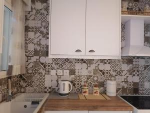 a kitchen with white cabinets and tiles on the wall at La Casa di Levante in Zakynthos