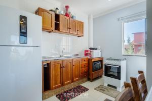 a kitchen with wooden cabinets and a white refrigerator at Apto 2 Quartos a 260m da Praia RIB0201 in Barra de Ibiraquera +7 photos