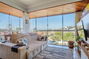 a living room with a couch and large windows at Apto 2 Quartos a 260m da Praia RIB0201 in Barra de Ibiraquera