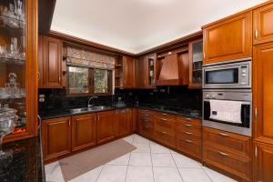a kitchen with wooden cabinets and black counter tops at Georgias paradise villa and Garden in Kamárai