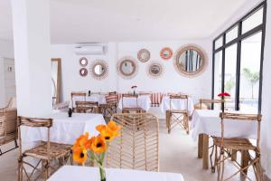 アビジャンにあるGoya Resorts & SPAのダイニングルーム(白いテーブル、椅子、鏡付)