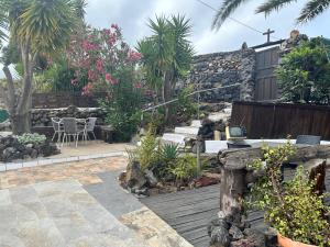 Un jardín con un muro de piedra y una terraza de madera. en El Sueño Del Angel, en Santa Cruz de la Palma