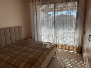 a bedroom with a bed and a large window at Everbright Seaside Serenity in Himare