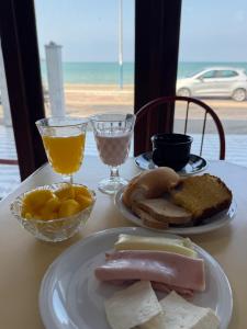 a table with two plates of food and glasses of orange juice at Pousada Maresia Praia in Rio das Ostras