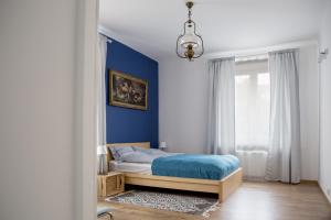 a bedroom with a bed with a blue wall at Santorini in Kołobrzeg
