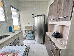 eine Küche mit einem Kühlschrank aus Edelstahl und einer Mikrowelle in der Unterkunft Guilhermina – apto pertinho da praia in Praia Grande