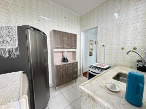 eine Küche mit einem Kühlschrank aus Edelstahl und einer Spüle in der Unterkunft Guilhermina – apto pertinho da praia in Praia Grande + 12 Fotos