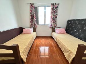 ein Zimmer mit zwei Betten und einem Fenster in der Unterkunft Guilhermina – apto pertinho da praia in Praia Grande