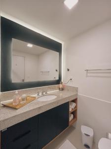 a bathroom with a sink and a large mirror at Apartamento Artsy in Itaipava