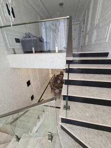 a glass staircase in a house with a man sitting in a chair at Luxury villa Gabala ELM in Gabala