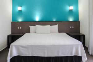 a bedroom with a large white bed with a blue wall at Hotel MX portal maya in Playa del Carmen