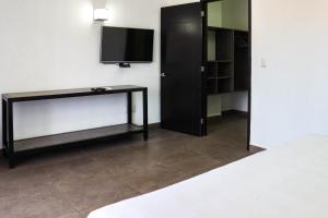a room with a tv and a table and a bed at Hotel MX portal maya in Playa del Carmen