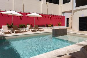 a pool with chairs and umbrellas next to a red wall at Hotel MX portal maya in Playa del Carmen +85 photos