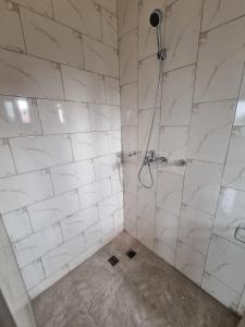 a bathroom with a shower with white tiles at IB's APARTMENT in Accra +13 photos