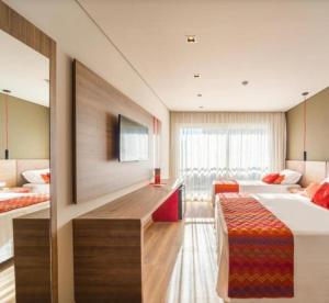 a hotel room with two beds and a tv at Hotel Laghetto stilo Borges in Gramado