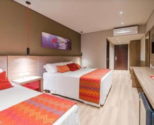 a hotel room with two beds and a table at Hotel Laghetto stilo Borges in Gramado