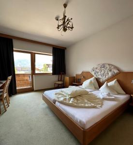 a bedroom with a large bed and a chandelier at Hotel Alpina nature-wellness in Wenns +46 photos