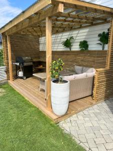 a wooden pergola with a couch and a grill at Large house with 3 bedrooms and a private garden in Stavanger