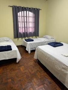 a room with three beds and a window at Casa NSA - Nossa Senhora Aparecida in Aparecida