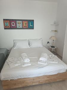 a bed with white sheets and towels on it at Iliada Suites Simousi Kythnos in Kithnos