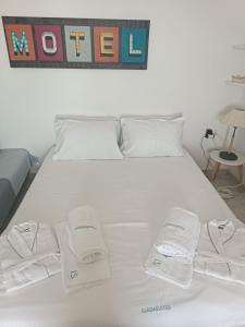 a white bed with three towels on it at Iliada Suites Simousi Kythnos in Kithnos