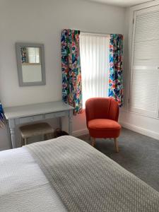 een slaapkamer met een bed en een rode stoel bij Ludford View, riverside cottage in Ludlow with private parking in Ludlow