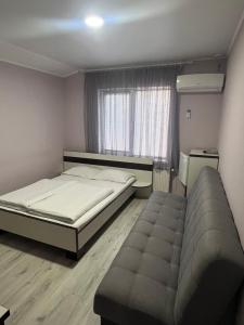 a bedroom with a bed and a couch and a window at Guest House MAX in Khmelnytskyi
