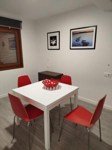 a white table with red chairs and a bowl on it at Apartamento Buño Malpica in Malpica