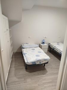 two twin beds in a room with white walls at Apartamento Buño Malpica in Malpica
