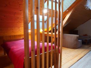 a bedroom with a red bed and a wooden staircase at Etage Bleu à la montagne in Saint-Julien-en-Champsaur